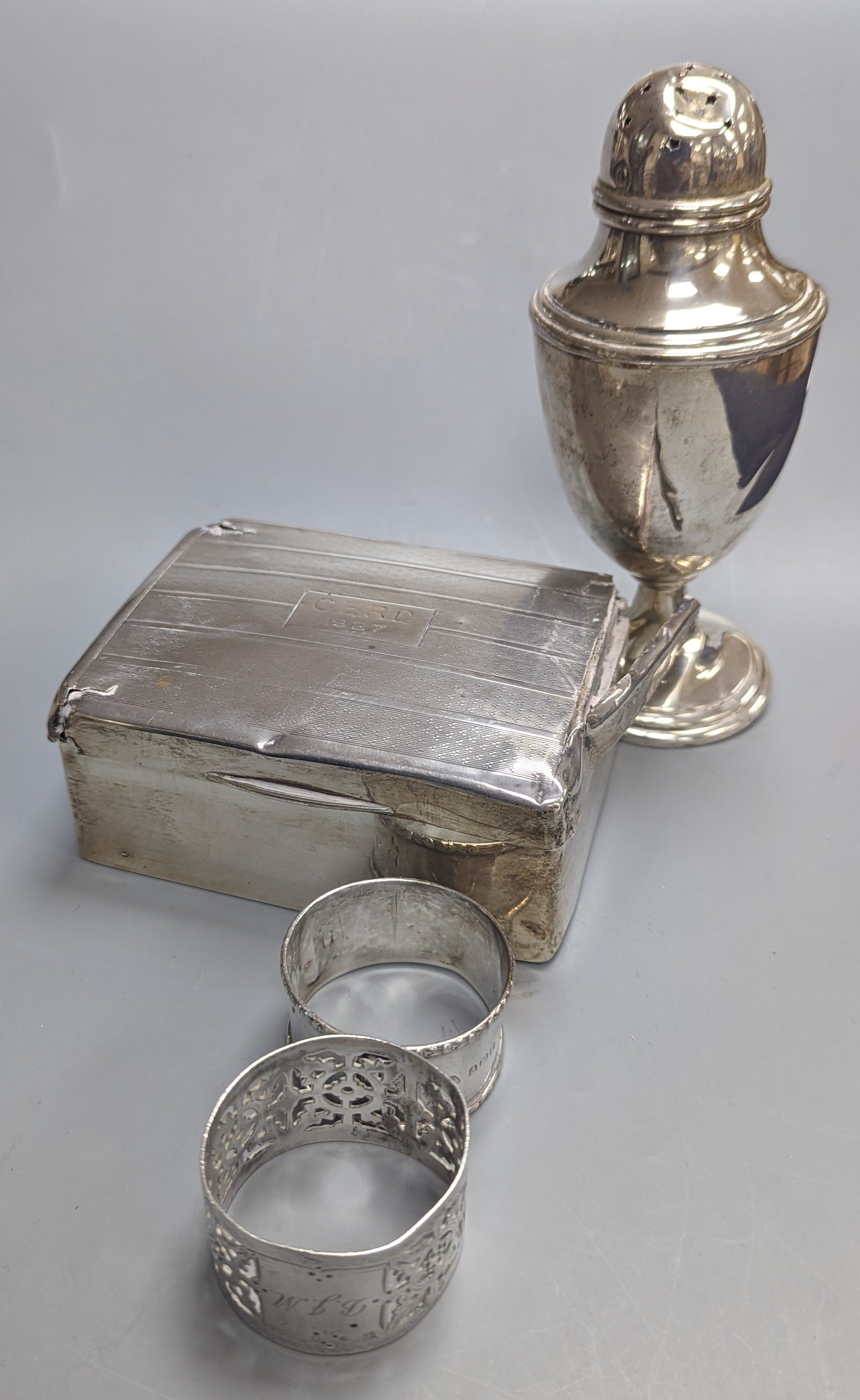 A silver cigarette case, four silver napkin rings, a cased part German 835 standard mirror and brush set, a group of small silver including condiments, sugar caster, cigarette box some damaged) and a group of assorted si